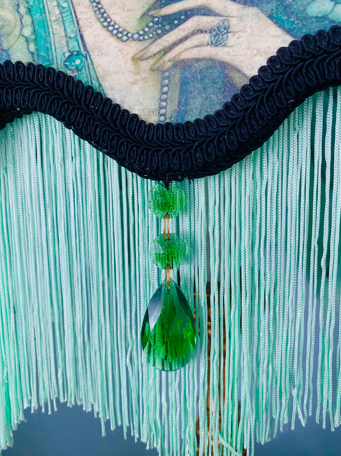 Close-up of emerald jewels – “Glass emerald jewels sparkling against green silk and black lace on an antique-inspired Victorian lampshade.”