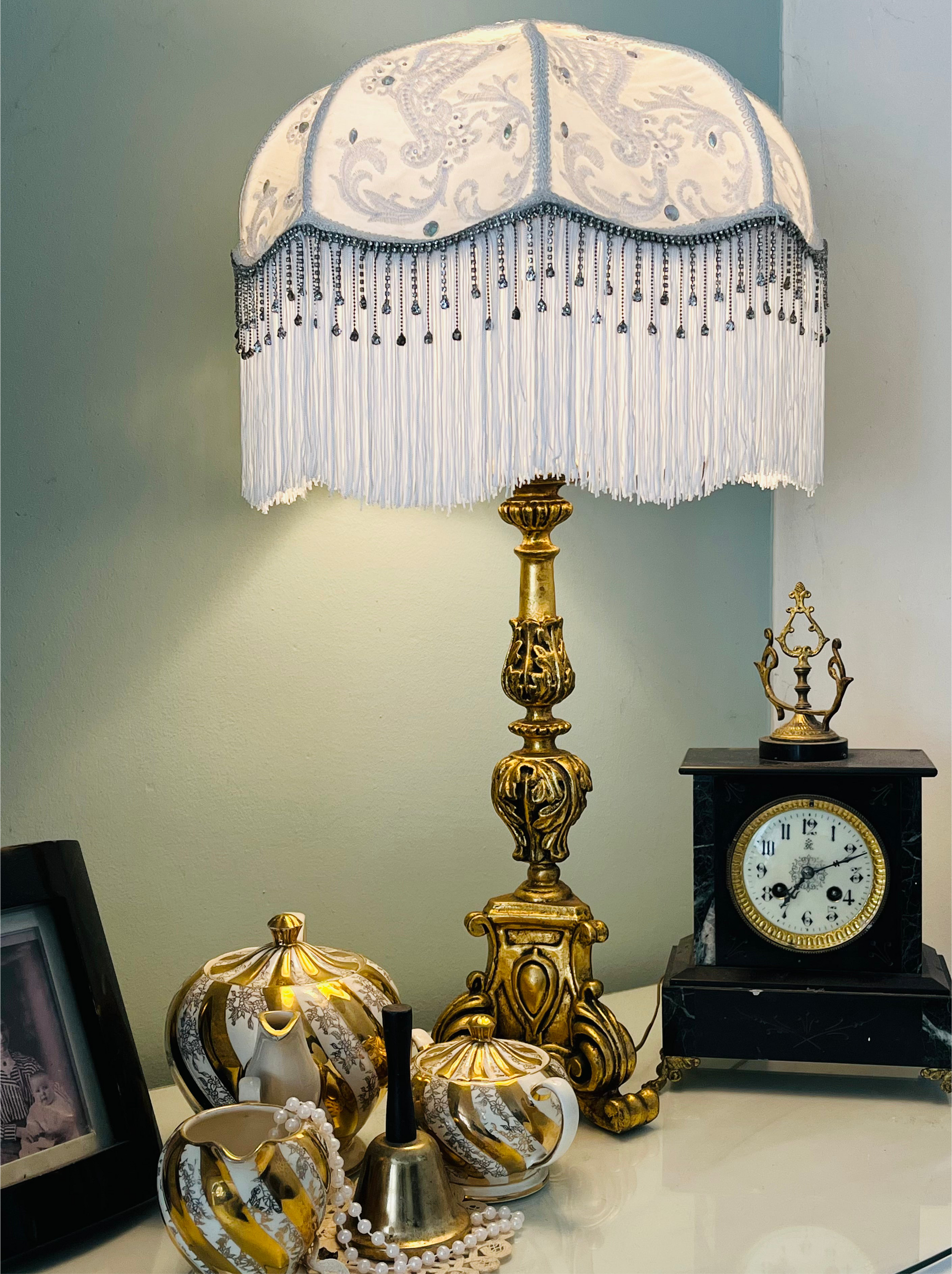 Full view – “Handmade white Victorian silk lampshade with lace overlay, diamante beading, long white fringe, and sparkling diamante trim.”lit up