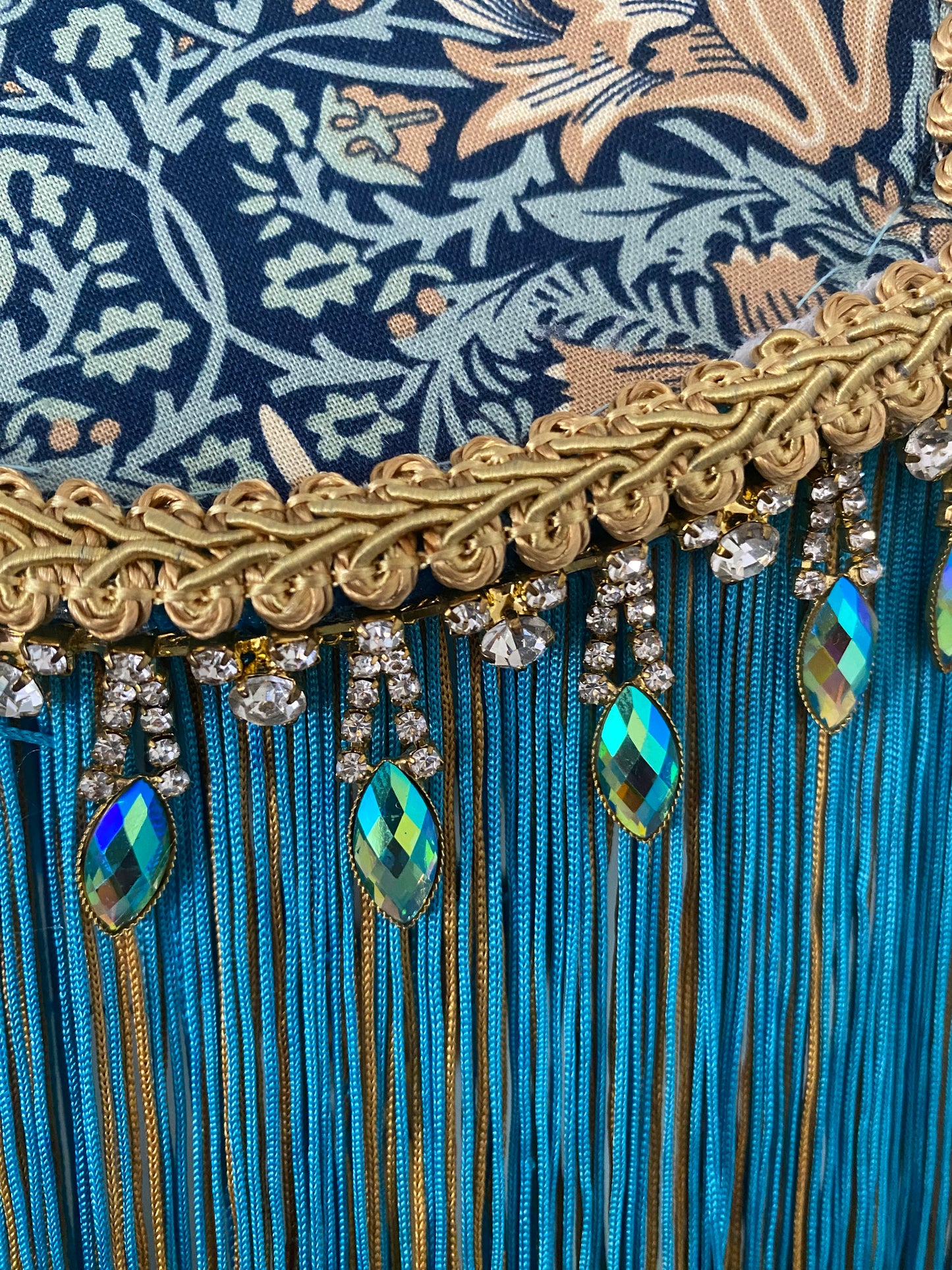 Close-up of trim
Detail of handmade William Morris “Snakeshead” turquoise Art Deco lampshade, showing gold braid edging with iridescent diamantés — elegant Victorian-style lighting with artisan craftsmanship.