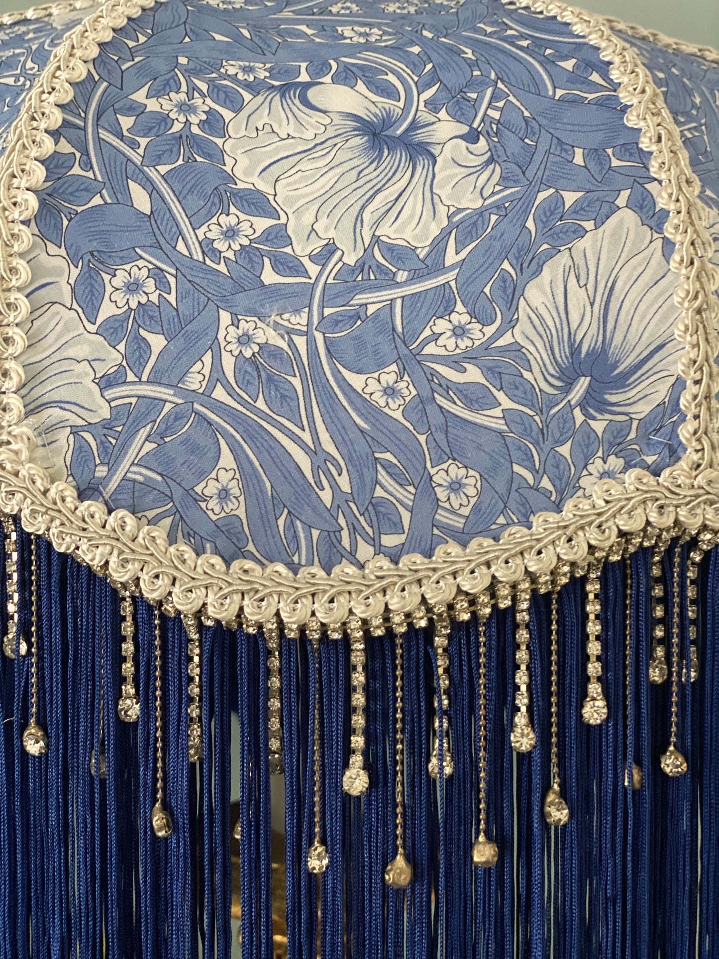 Close-up of fabric pattern – “Detailed close-up of William Morris ‘Pimpernel’ pattern on a handmade Victorian lampshade with navy blue fringe and crystal beaded trim.”