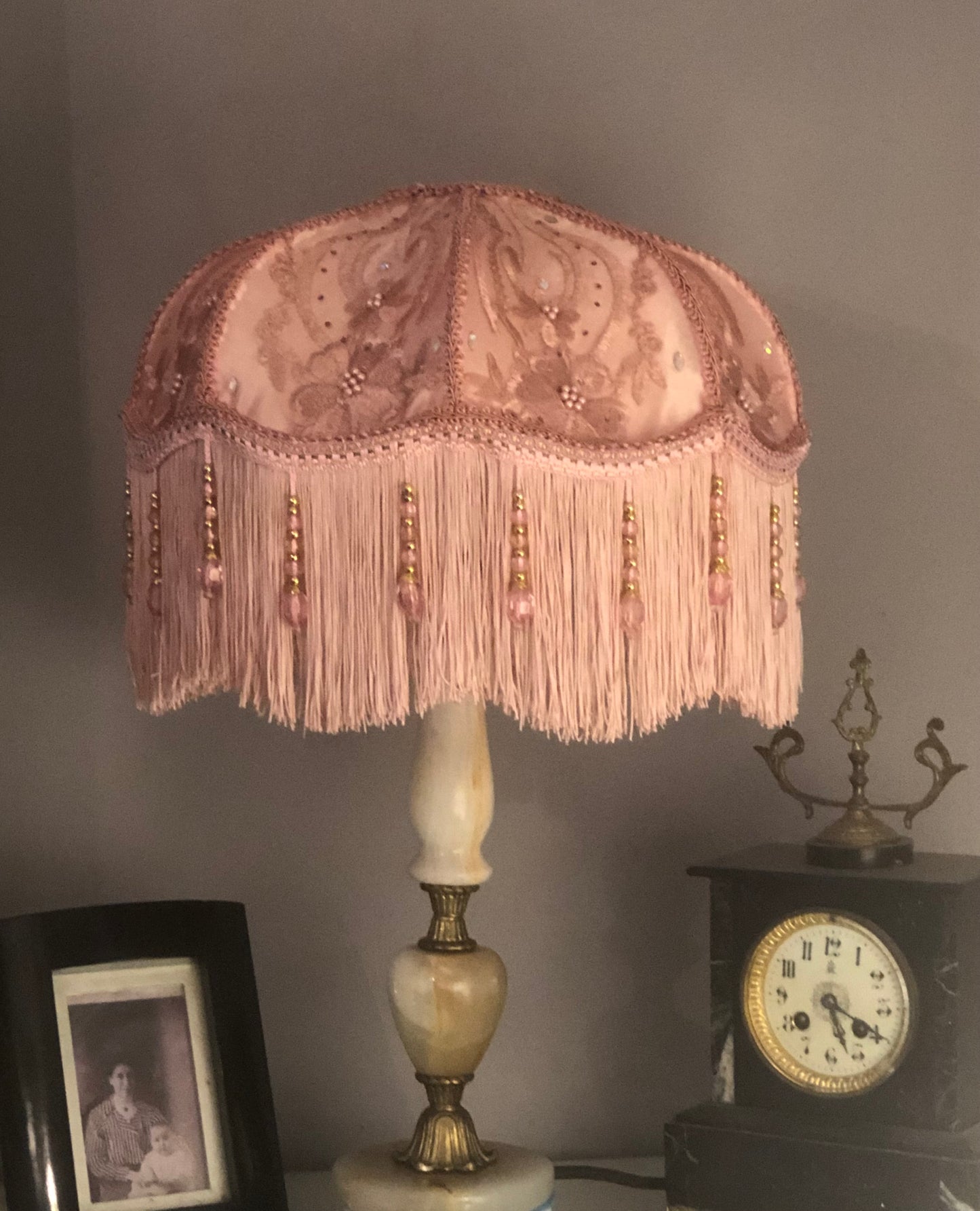 Lifestyle / styled setting – “Pink floral Victorian lampshade with diamante sparkle and fringe, styled in a feminine vintage room – handmade luxury lighting accent.” with clock and photo