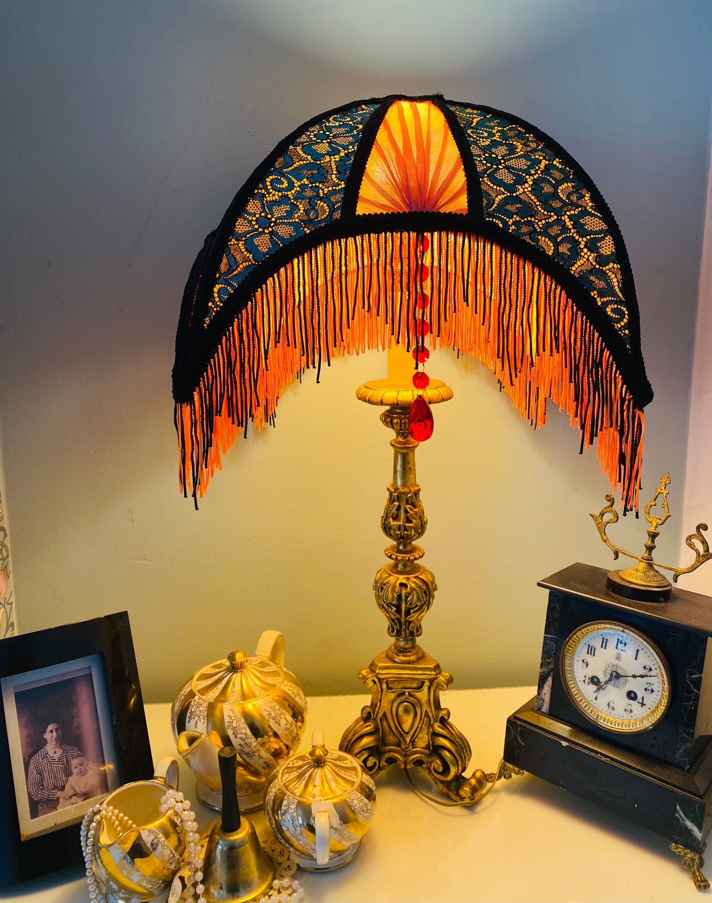 Lit lamp “Art Deco crescent silk lampshade illuminated to reveal red pleats orange  fringe