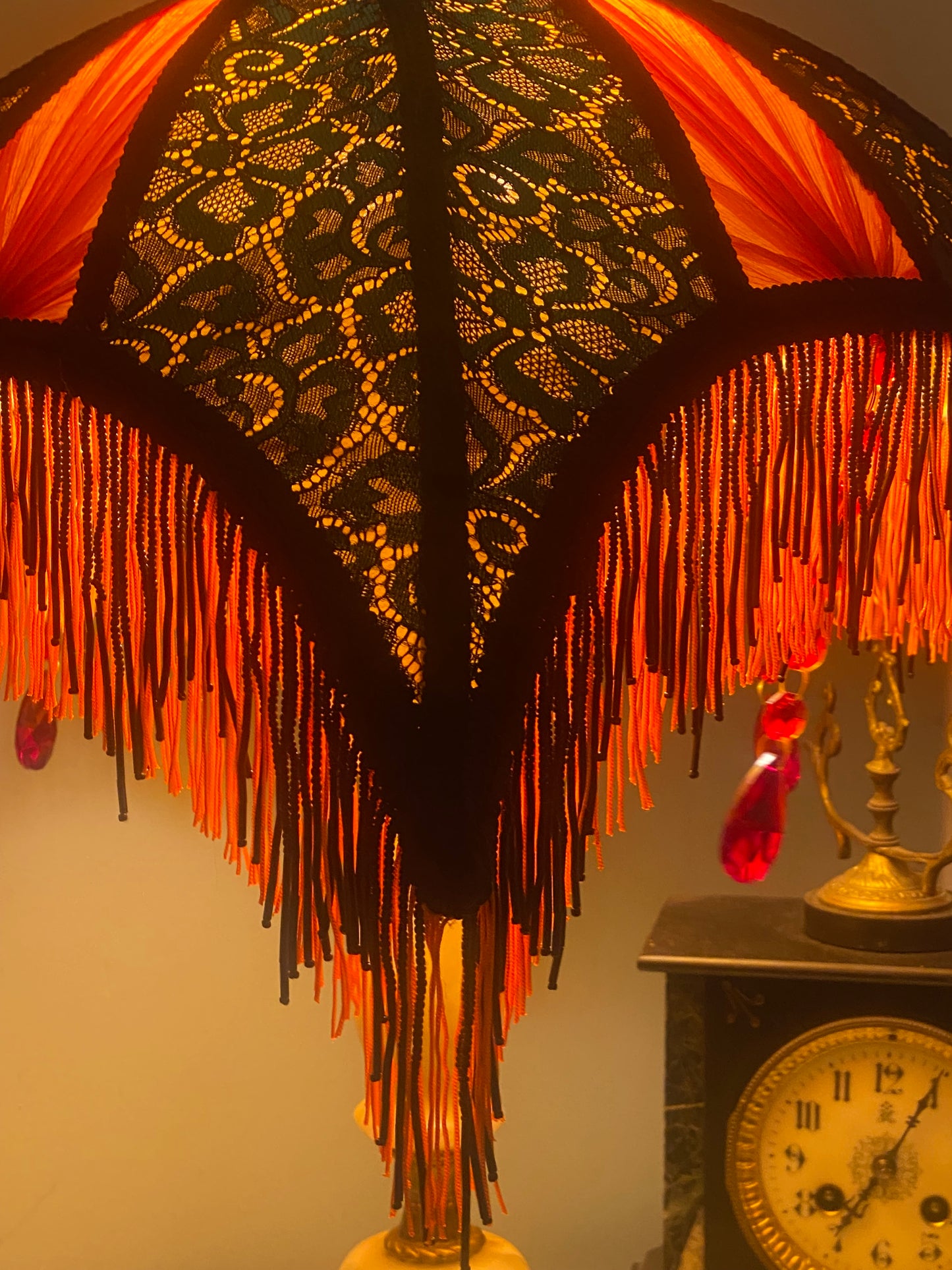 6. Angled view of the lampshade illuminated, showing the interplay of colors as the jade green lace and red chiffon glow against the orange silk base. Corner view