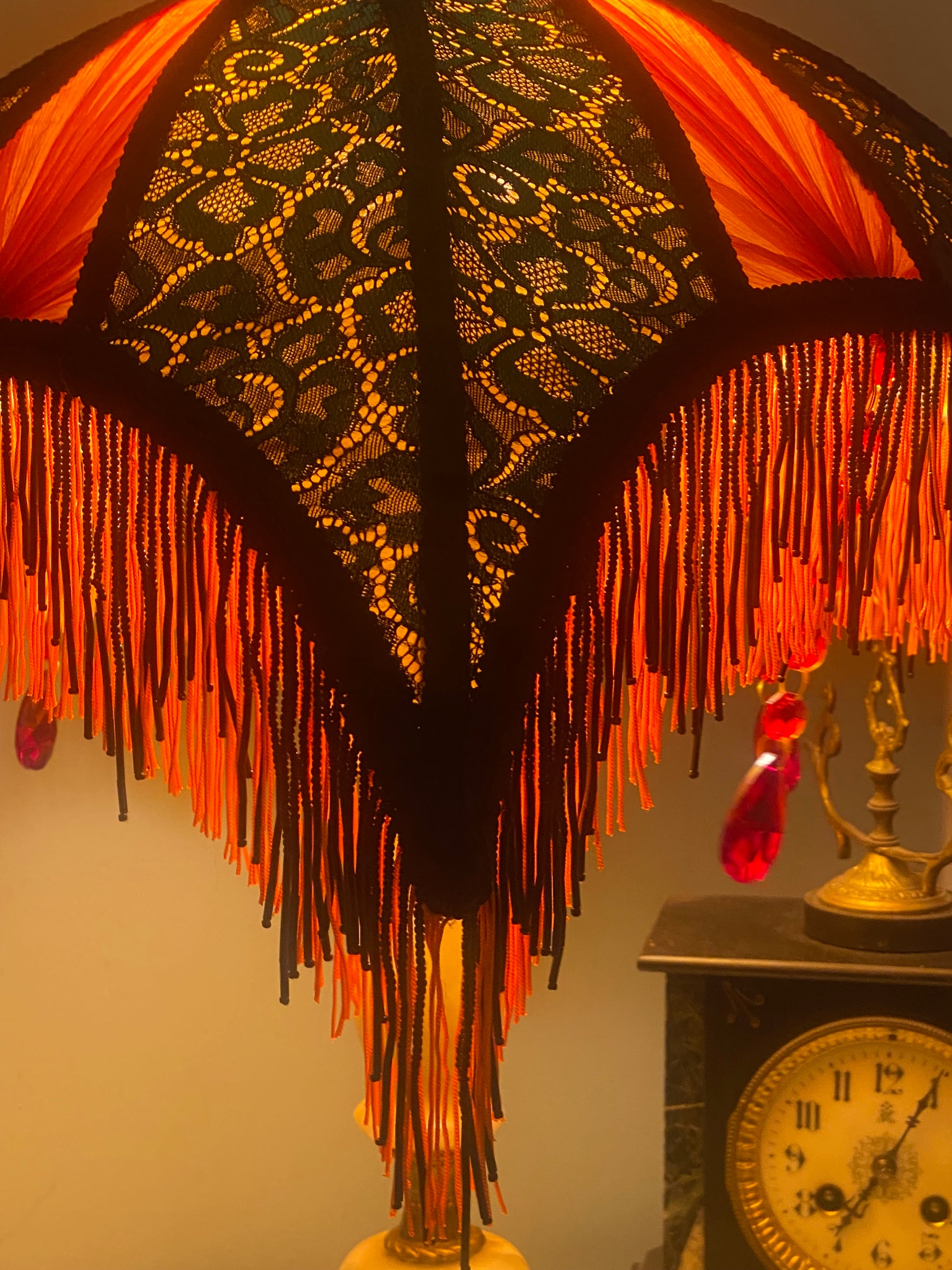 6. Angled view of the lampshade illuminated, showing the interplay of colors as the jade green lace and red chiffon glow against the orange silk base. Corner view