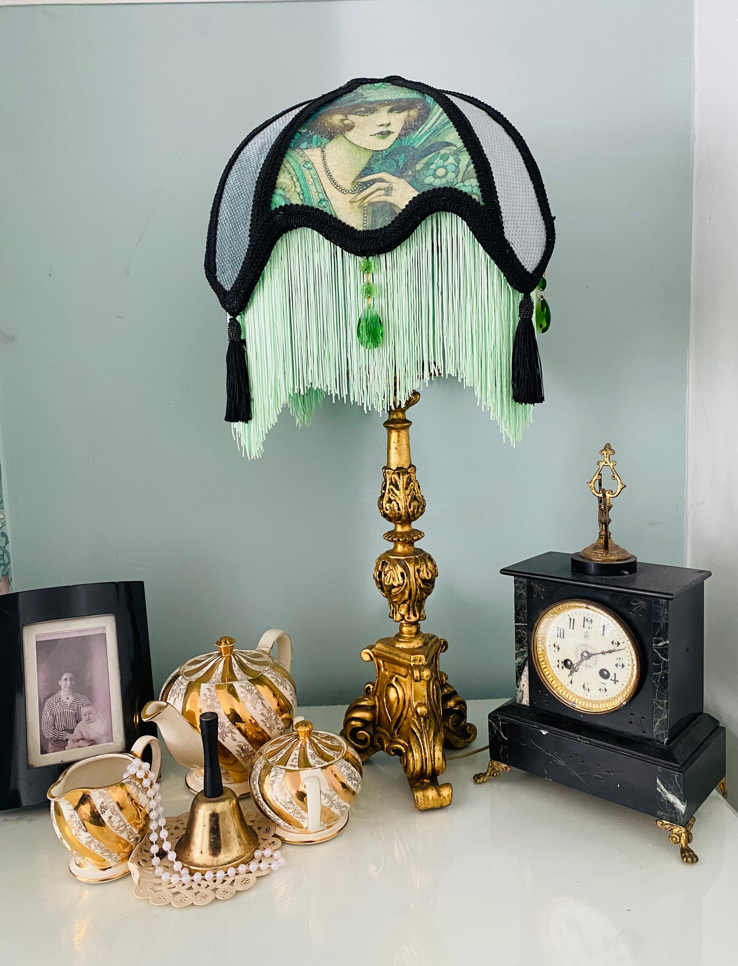 Full view – “Handmade Victorian parlour lampshade featuring an Edwardian lady image, black lace over green silk and velvet panels, with glowing green fringe and glass emerald jewels.”